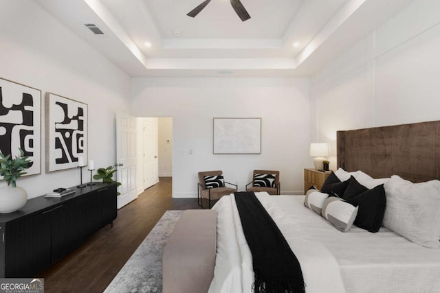 bedroom with a raised ceiling, ceiling fan, dark hardwood / wood-style flooring, and a high ceiling