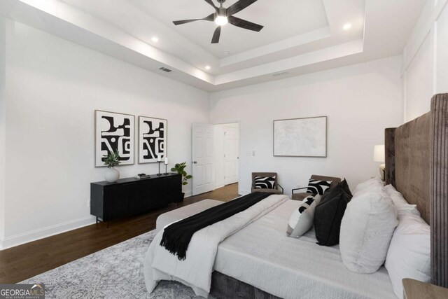 bedroom featuring dark hardwood / wood-style floors, ceiling fan, and a raised ceiling