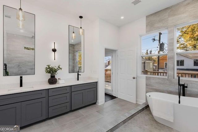 bathroom with tile patterned flooring, vanity, a bathtub, and tile walls