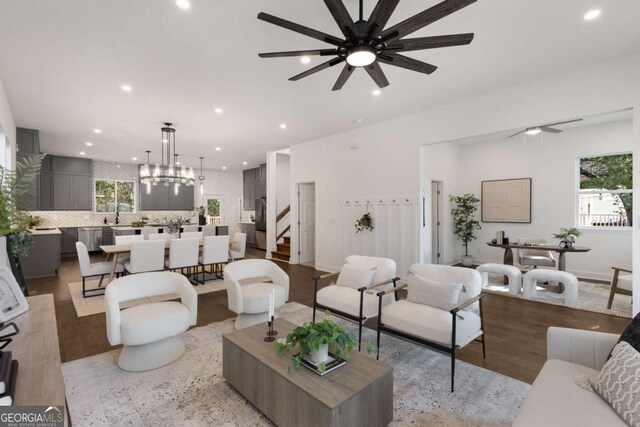 living room with a healthy amount of sunlight, ceiling fan with notable chandelier, and light hardwood / wood-style floors