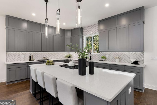 kitchen featuring gray cabinets, a kitchen island, hanging light fixtures, and dark wood-type flooring