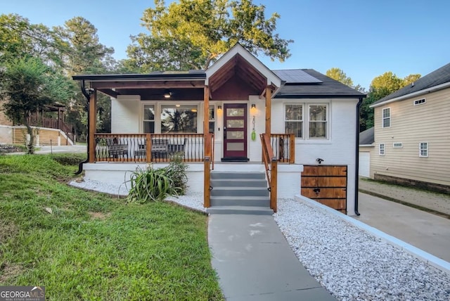 bungalow featuring a front yard, a porch, and solar panels