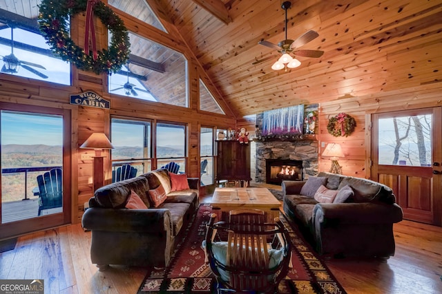 living room with wood-type flooring, high vaulted ceiling, a wealth of natural light, and wood walls