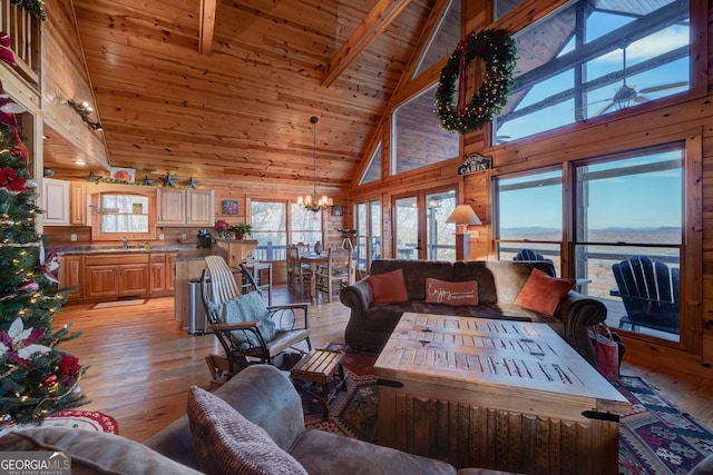 living room featuring beam ceiling, high vaulted ceiling, light hardwood / wood-style floors, and a notable chandelier