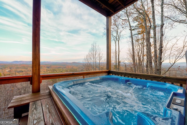 deck at dusk featuring a mountain view and an outdoor hot tub