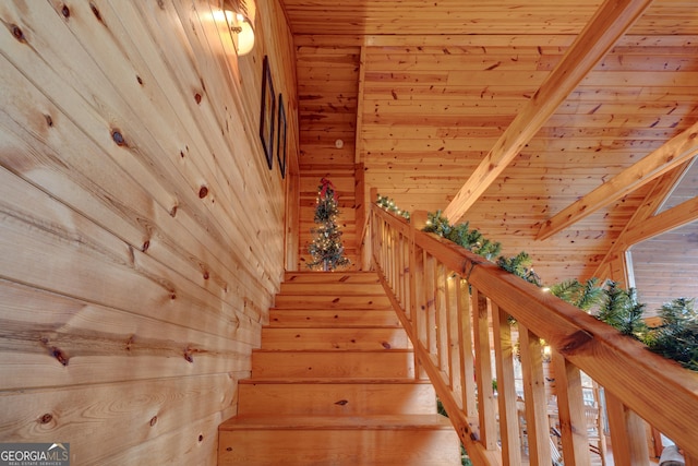 staircase featuring beamed ceiling, wood walls, and wooden ceiling