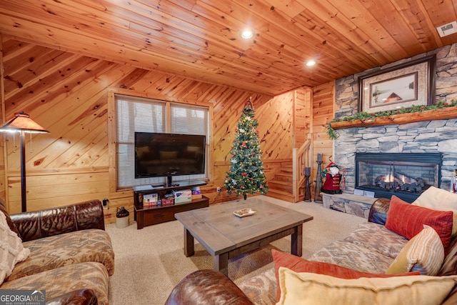 carpeted living room featuring wooden ceiling, a stone fireplace, and wooden walls