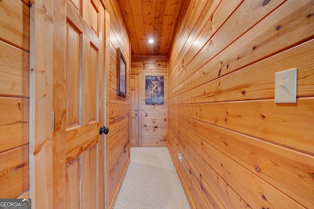 hall featuring wood walls, light colored carpet, and wooden ceiling