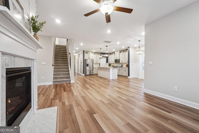 unfurnished living room with ceiling fan, light wood-type flooring, and a premium fireplace