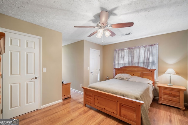 bedroom featuring light wood-type flooring, baseboards, a textured ceiling, and ceiling fan