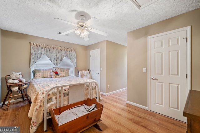 bedroom featuring ceiling fan, light hardwood / wood-style floors, and a textured ceiling