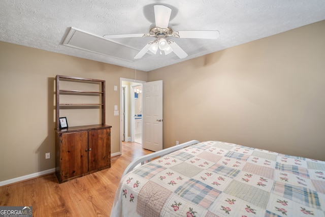 bedroom with a textured ceiling, light wood-type flooring, and ceiling fan