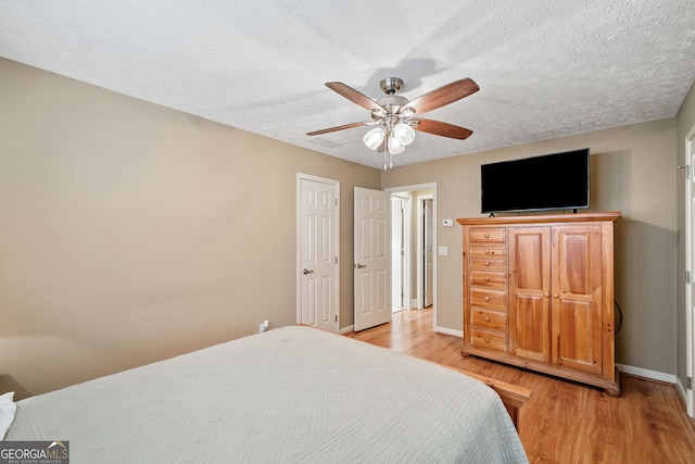 bedroom featuring a textured ceiling, light hardwood / wood-style floors, and ceiling fan