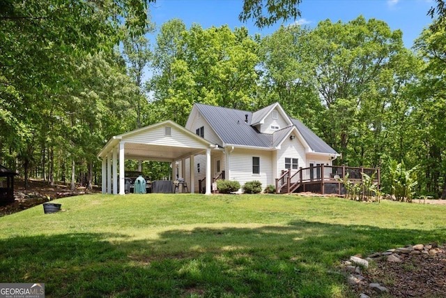 rear view of house featuring a yard, a deck, metal roof, and a carport