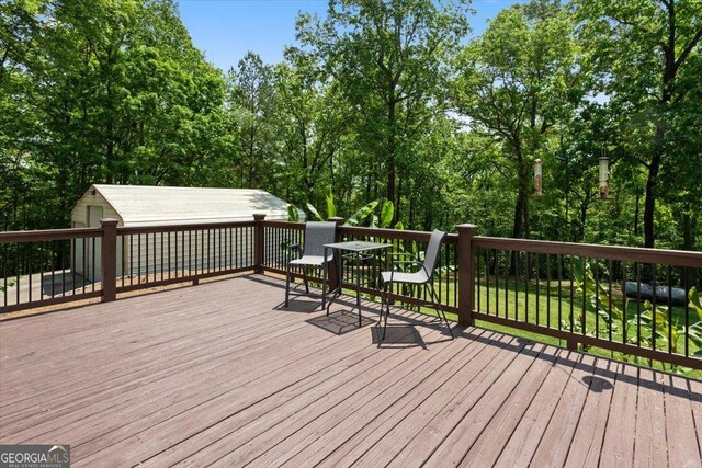 deck with an outdoor structure and view of wooded area