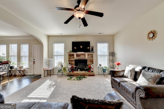 living room with a fireplace, ceiling fan, hardwood / wood-style floors, and ornamental molding