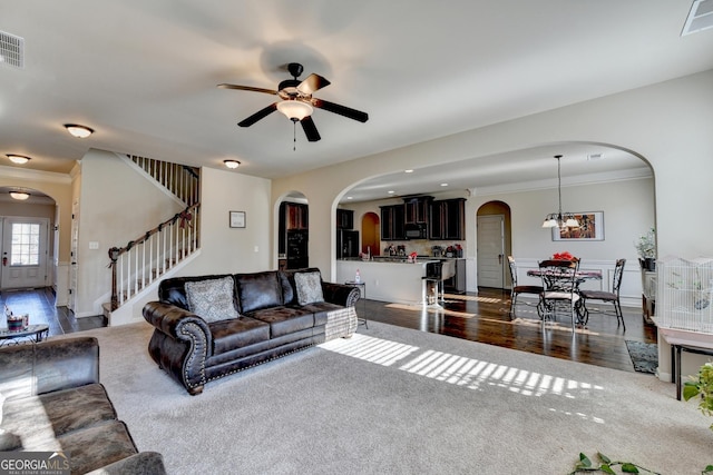 living room featuring ceiling fan with notable chandelier, dark hardwood / wood-style flooring, and ornamental molding