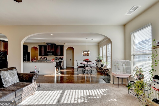 living room featuring ornamental molding, light wood-type flooring, and a notable chandelier