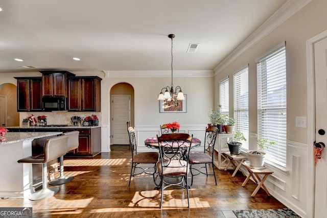 dining area with ornamental molding, dark wood-type flooring, and a chandelier