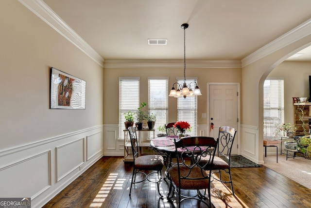 dining area featuring dark hardwood / wood-style floors, crown molding, and a notable chandelier