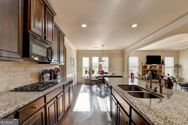 kitchen featuring dark hardwood / wood-style flooring, light stone counters, dark brown cabinetry, stainless steel appliances, and sink