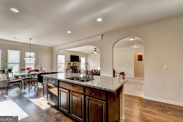 kitchen featuring sink, hanging light fixtures, dark hardwood / wood-style floors, a kitchen island with sink, and ceiling fan with notable chandelier