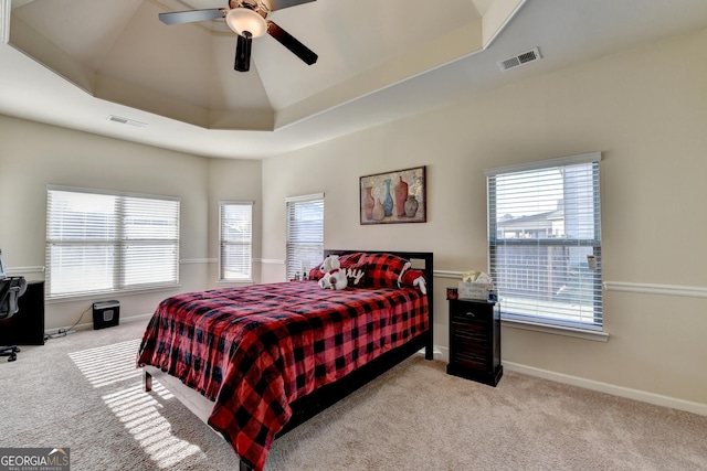 carpeted bedroom featuring ceiling fan and a raised ceiling