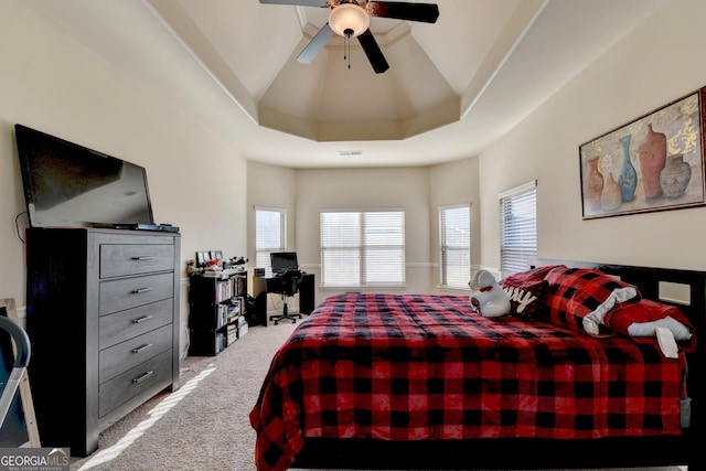 carpeted bedroom with a tray ceiling, ceiling fan, and vaulted ceiling