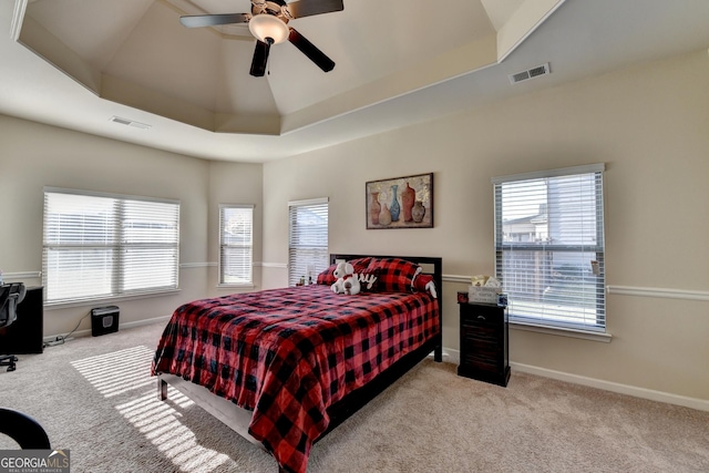 bedroom with a tray ceiling, multiple windows, and ceiling fan