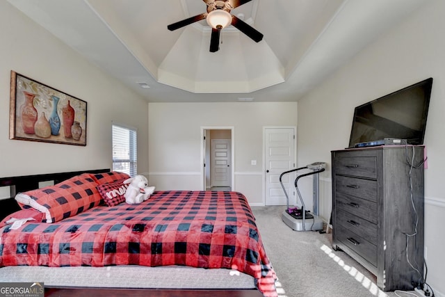 carpeted bedroom with a raised ceiling and ceiling fan