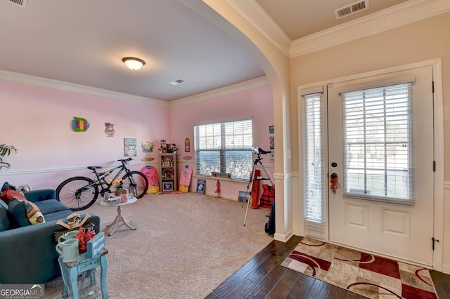 foyer entrance with plenty of natural light, ornamental molding, and dark wood-type flooring