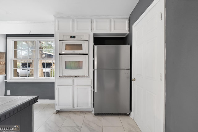 kitchen featuring stainless steel fridge, white cabinetry, and double oven