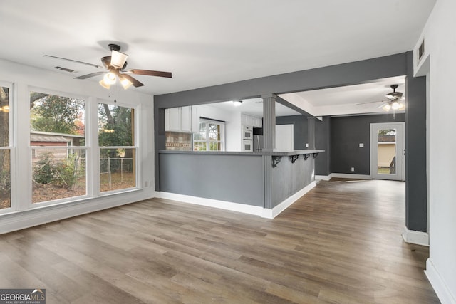 interior space featuring a kitchen bar, kitchen peninsula, hardwood / wood-style floors, and white cabinets