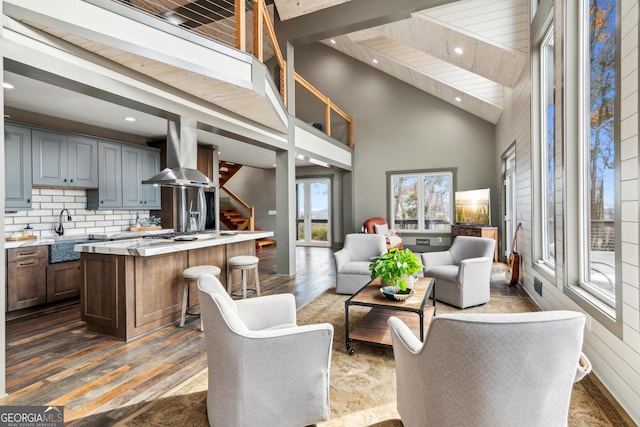 living room with sink, dark wood-type flooring, a high ceiling, and beam ceiling