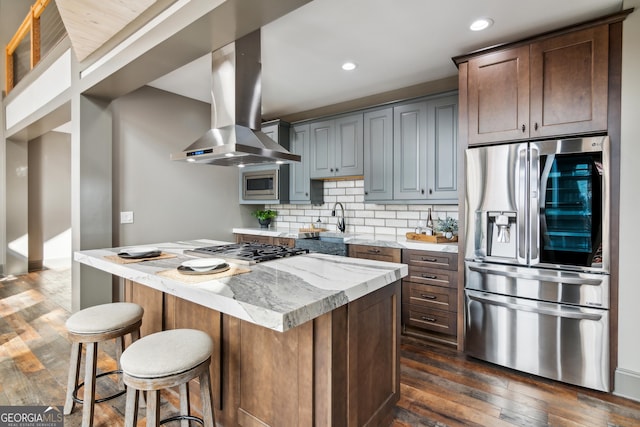 kitchen featuring exhaust hood, a center island, stainless steel appliances, dark hardwood / wood-style flooring, and decorative backsplash