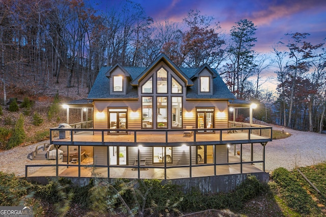 back house at dusk with french doors and a wooden deck