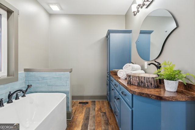 bathroom with a bath, hardwood / wood-style flooring, and vanity