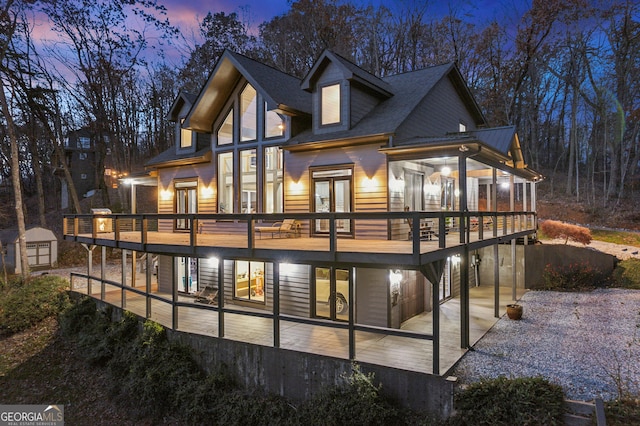 back house at dusk with a shed, french doors, a deck, and a patio