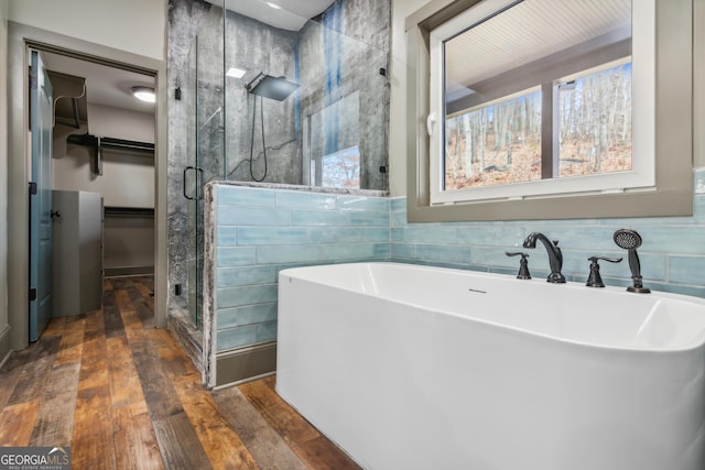 bathroom featuring plus walk in shower, wood-type flooring, and tile walls