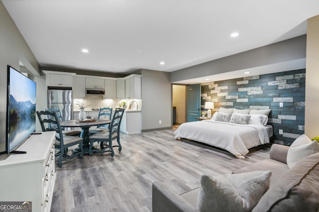 bedroom featuring light wood-type flooring and stainless steel refrigerator