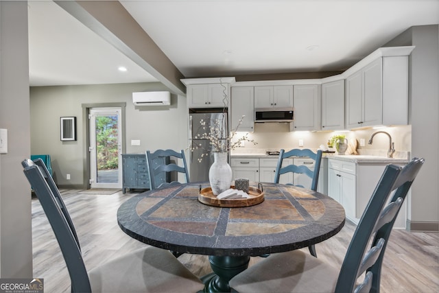 dining space with sink, light hardwood / wood-style flooring, and a wall unit AC