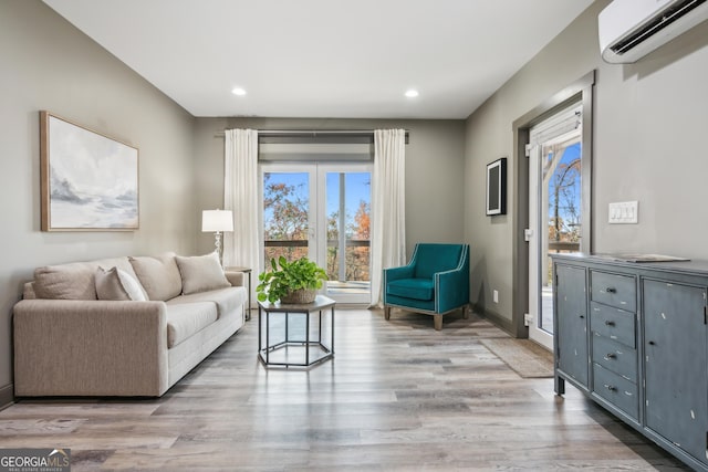 living room with a wall mounted AC, plenty of natural light, and wood-type flooring