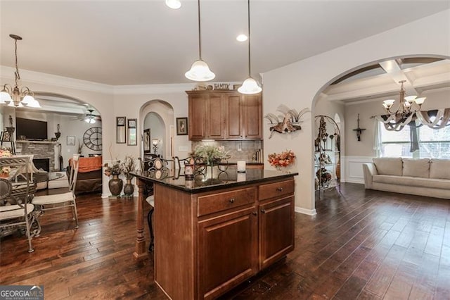 kitchen featuring a breakfast bar, pendant lighting, a kitchen island, and dark wood-type flooring