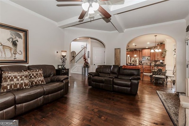 living room featuring beamed ceiling, ceiling fan with notable chandelier, ornamental molding, and dark wood-type flooring