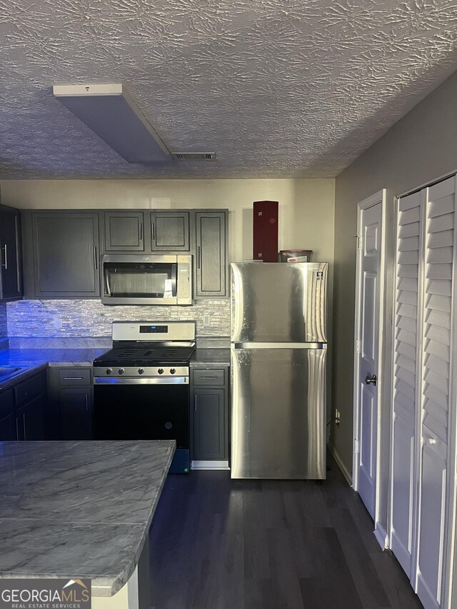 kitchen with gray cabinets, decorative backsplash, dark hardwood / wood-style flooring, and appliances with stainless steel finishes