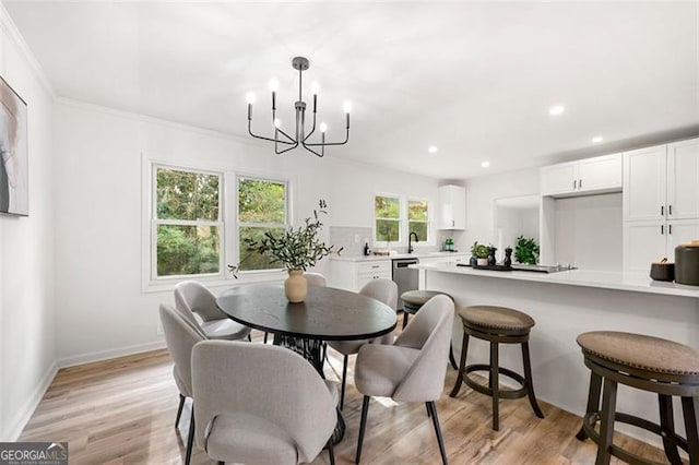 dining room featuring sink, light hardwood / wood-style flooring, a notable chandelier, and ornamental molding