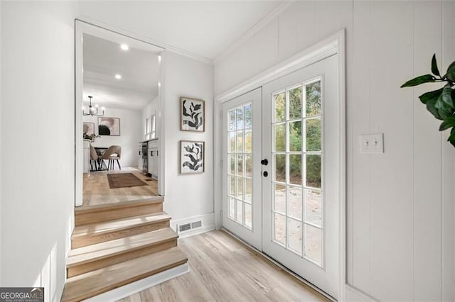 doorway to outside with a notable chandelier, light wood-type flooring, crown molding, and french doors