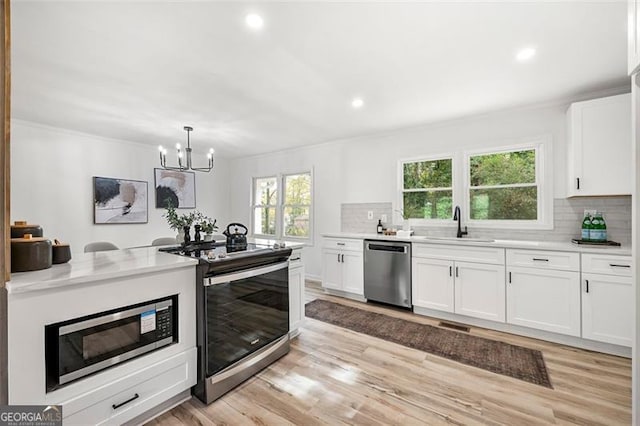 kitchen with white cabinets, light wood-type flooring, stainless steel appliances, and tasteful backsplash