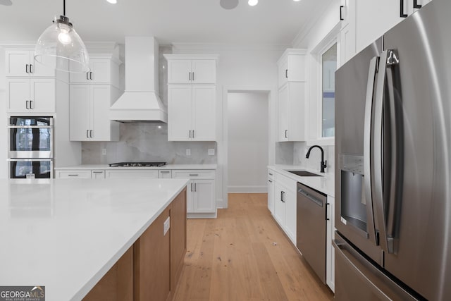 kitchen with backsplash, custom exhaust hood, stainless steel appliances, and a sink