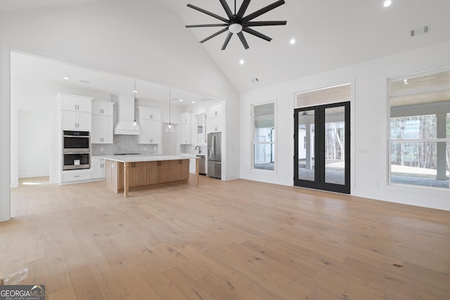 kitchen with visible vents, open floor plan, custom exhaust hood, stainless steel appliances, and light countertops